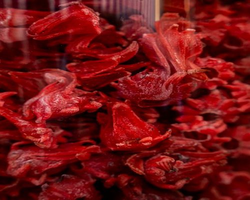 Deep red dried hibiscus flower calyces scattered inside an elegant earthen bowl