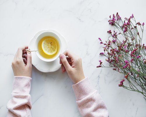 Freshly cut lemons being squeezed directly into a clean mug of boiled water