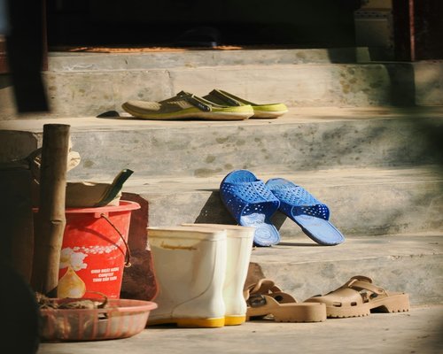 A clean domestic entryway with an organized shoe rack and automated hand washing station representing simple hygiene transitions